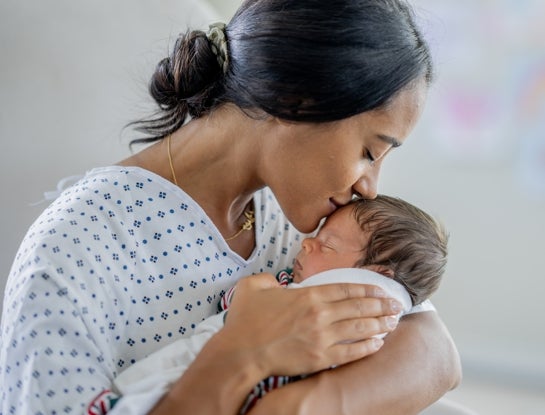 A woman holding and kissing her newborn