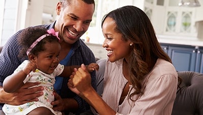 A couple playing with their infant on the couch