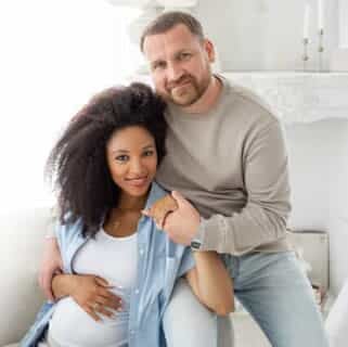 A man being embraced by his pregnant wife