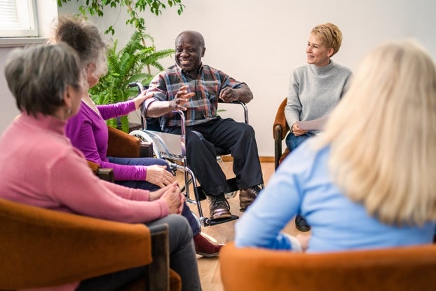 A man in a wheelchair speaking amongst a group of women in a sitting circle